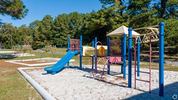 a playground with a swing set and slides in a park